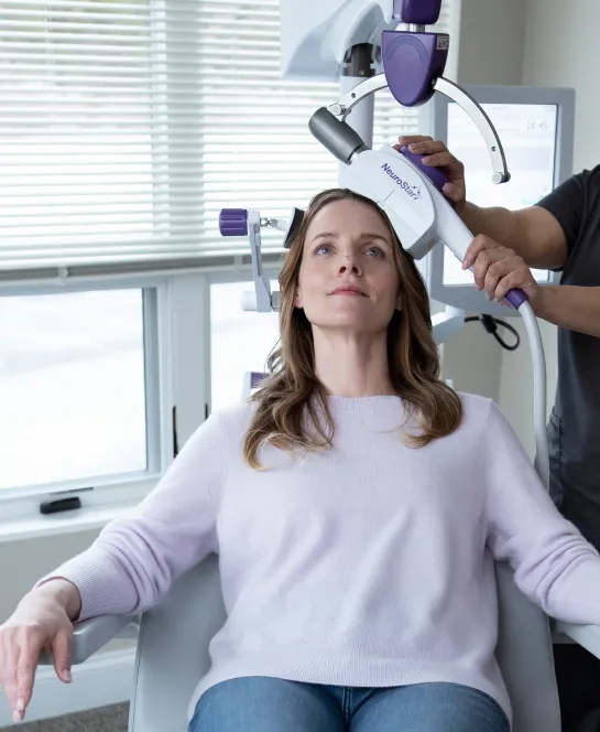 Deep TMS (BrainsWay) treatment in a calm clinic setting with a patient and clinician.