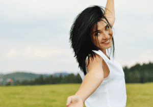 A woman in white shirt and blue skirt standing on grass.